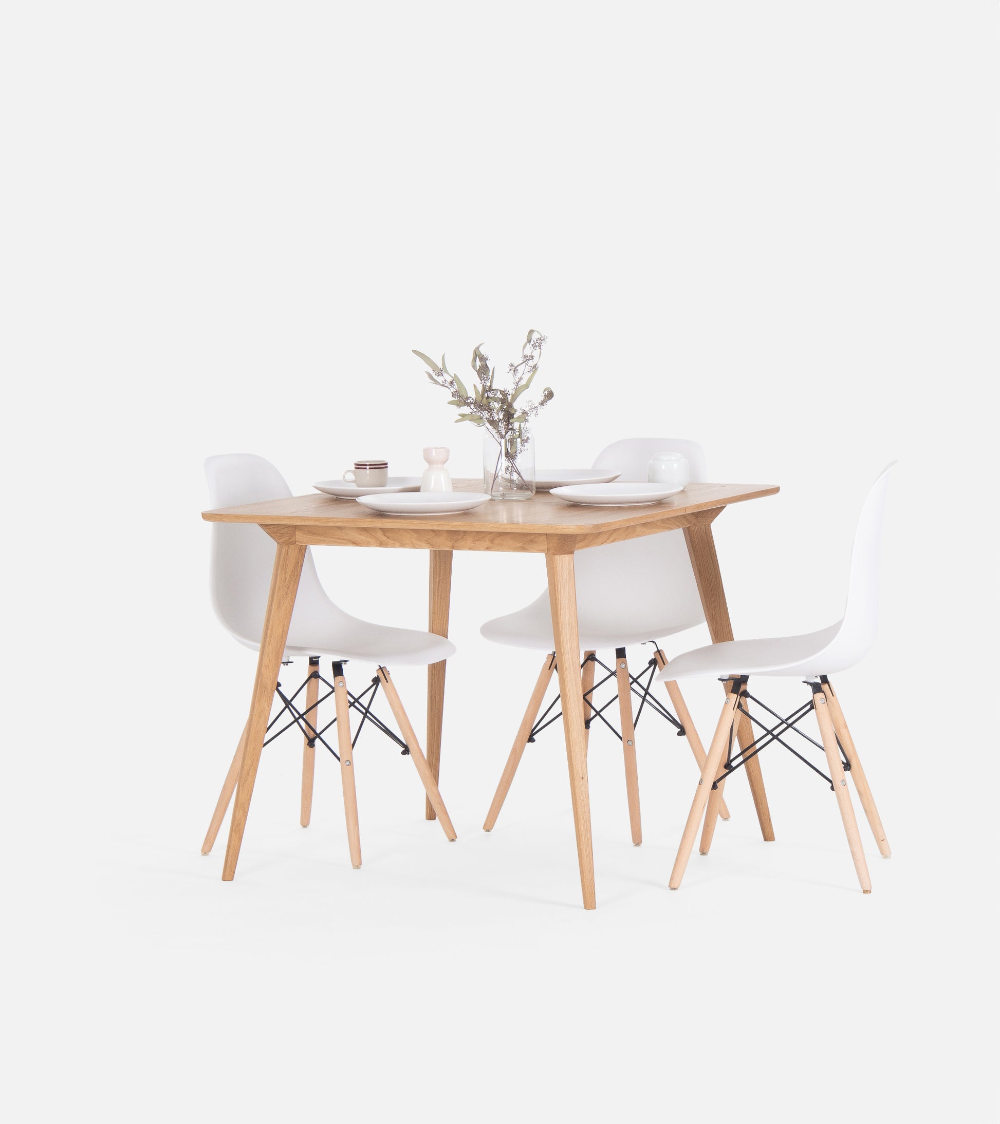 Minimalist dining set with a wooden table, four white chairs, and a vase with flowers.