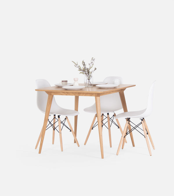 Minimalist dining set with a wooden table, four white chairs, and a vase with flowers.