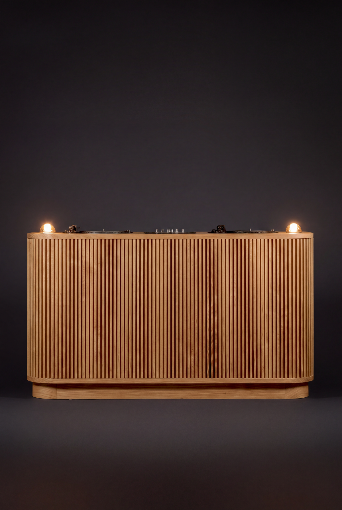 LOOP in solid oak, seen from the audience side against a dark background with both glass dome lights lit