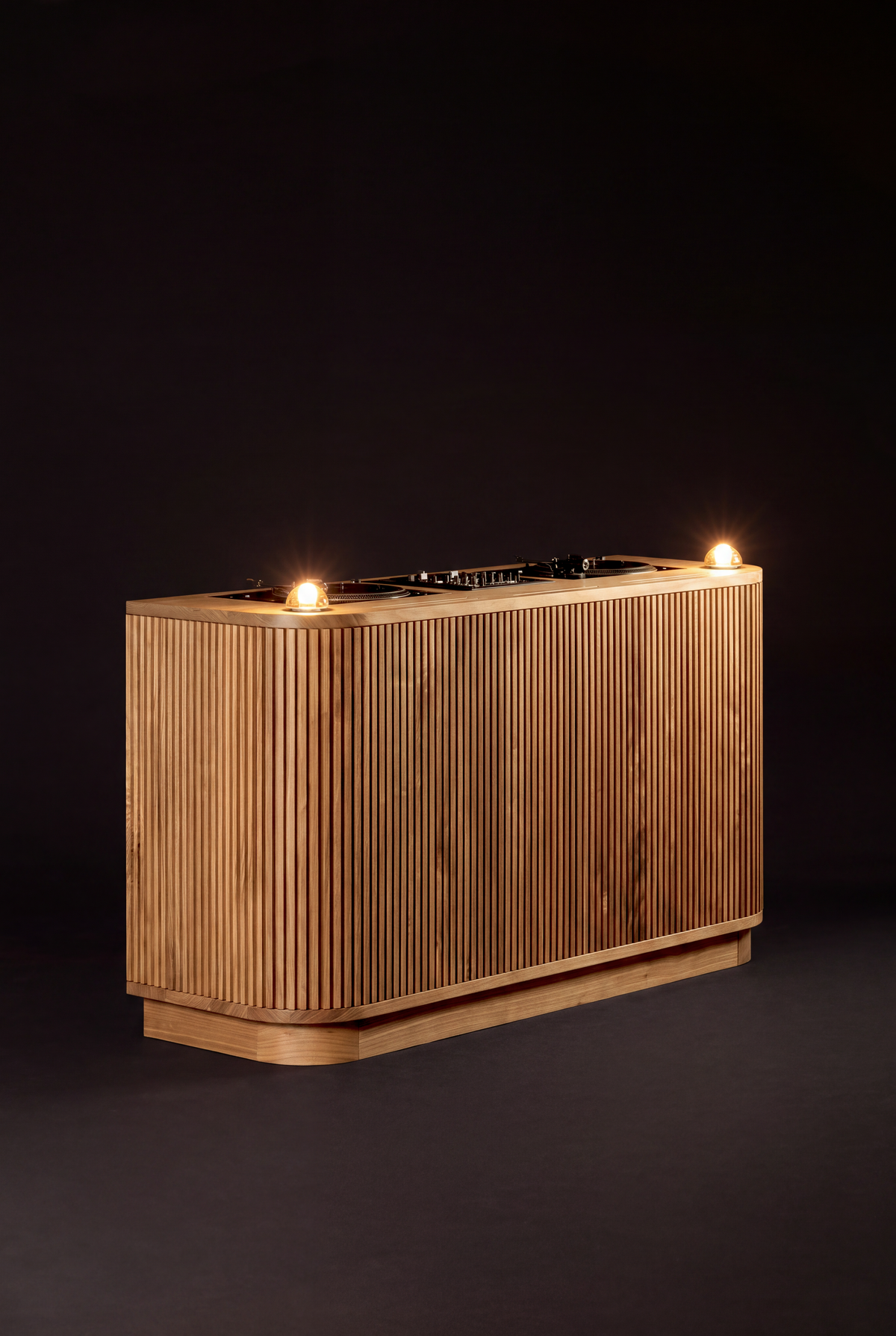 Angled view of LOOP in solid oak against a dark background, with both glass dome lights lit and the plinth visible