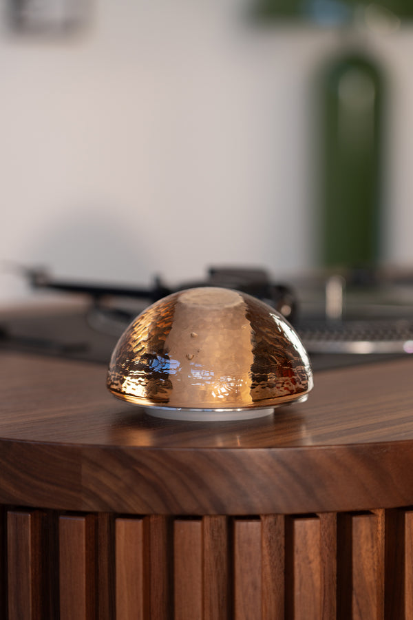 A dome-shaped object on a wooden surface, with blurred background elements.