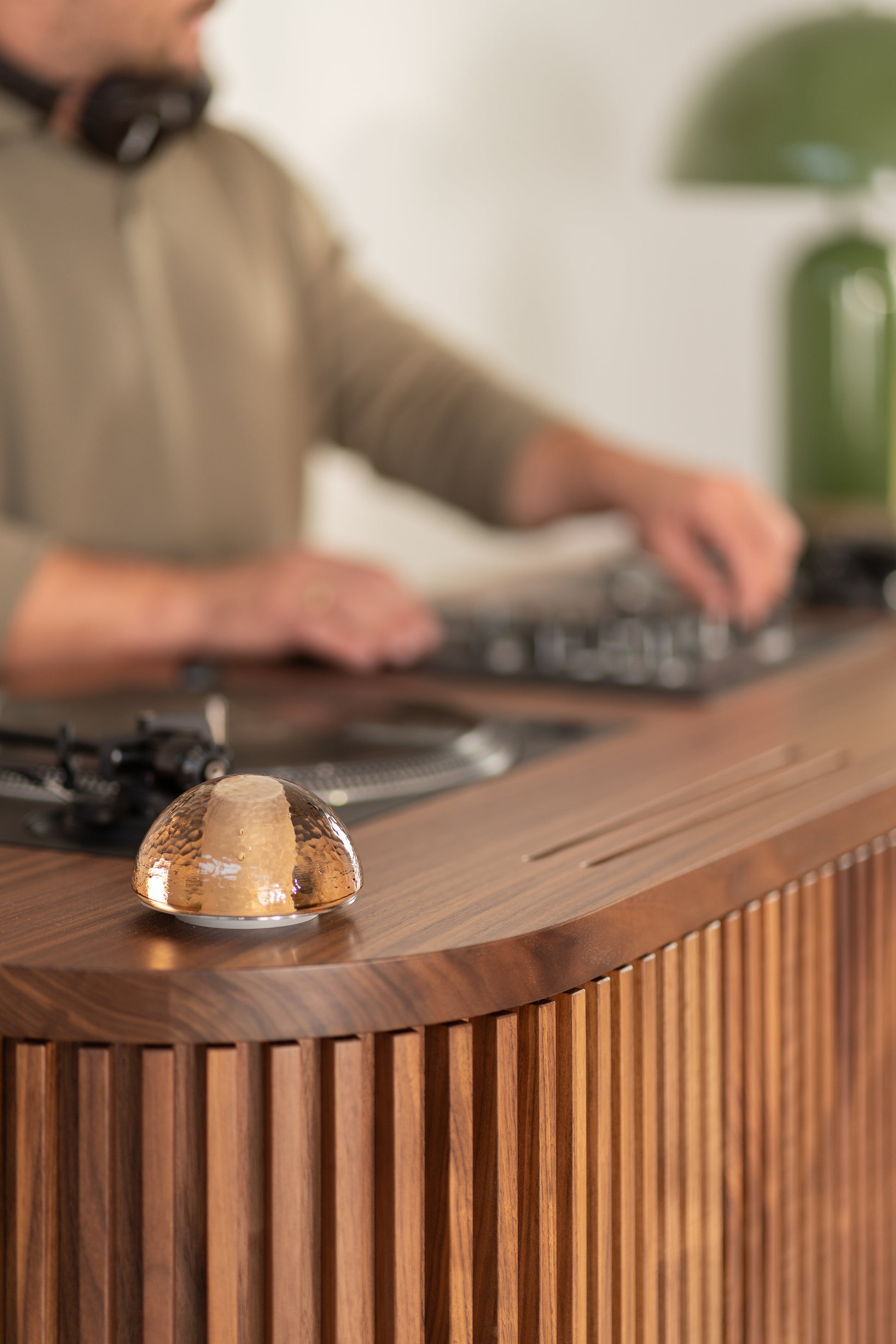 A person using DJ equipment on a wooden table, with a small glass dome in focus.