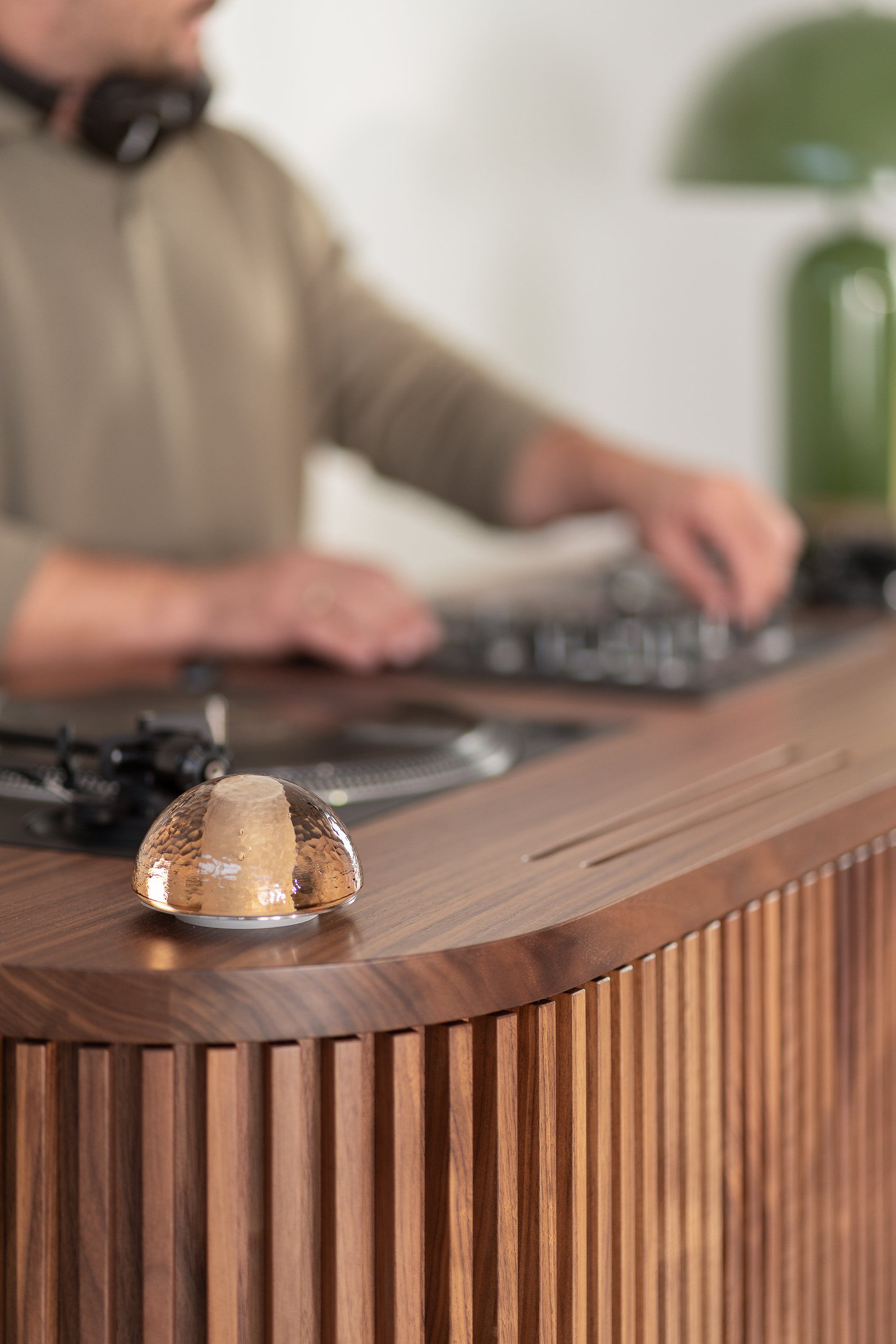 A person using DJ equipment on a wooden table, with a small glass dome in focus.