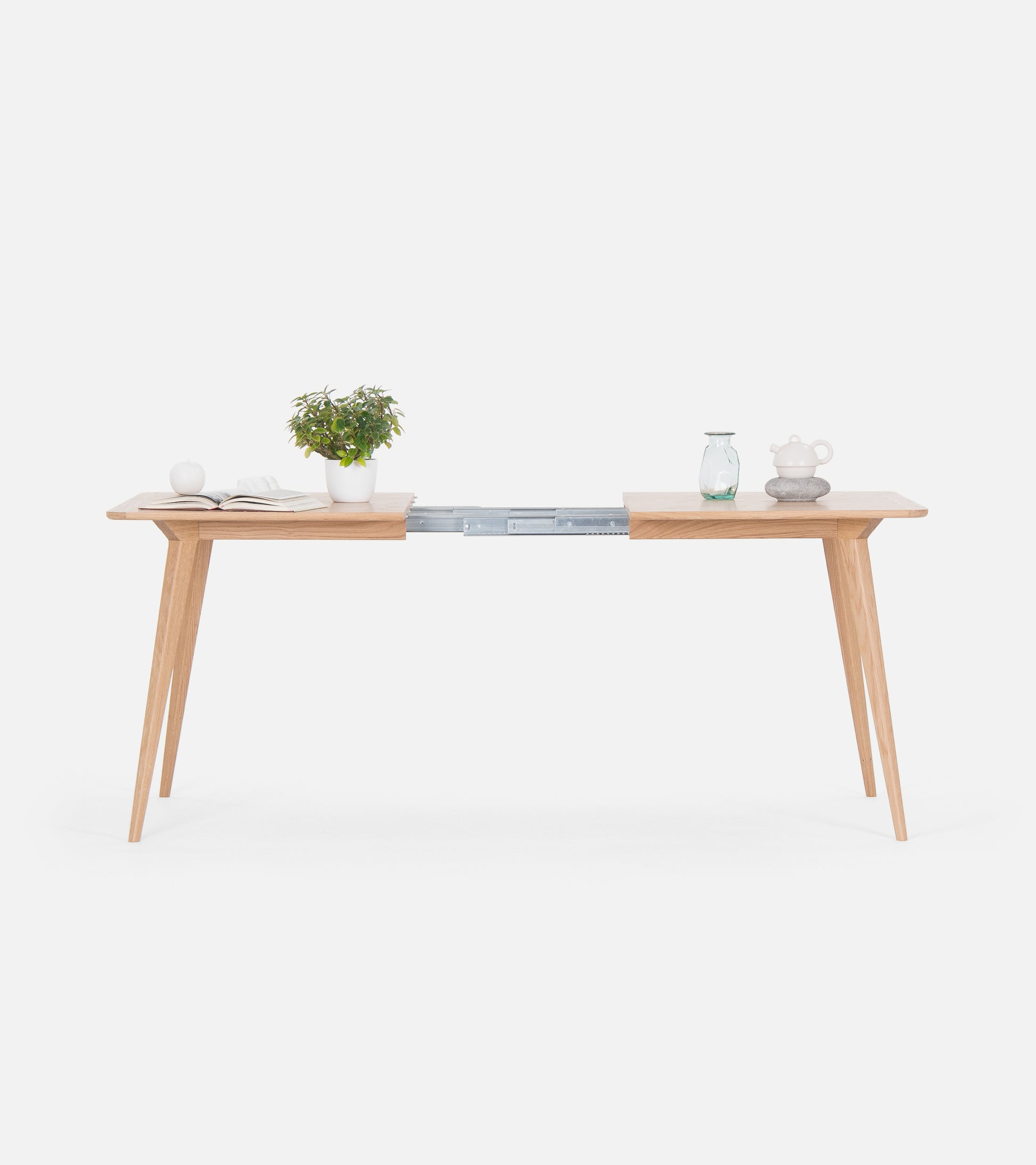 Minimalist wooden table with plants and ornaments, featuring a sliding extension in the middle.