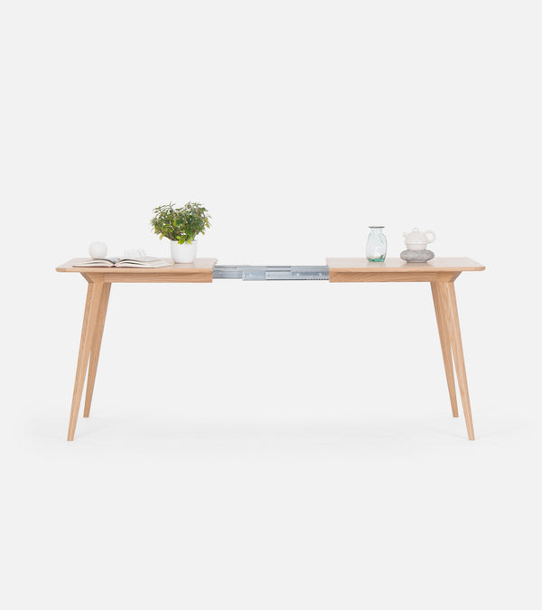 Minimalist wooden table with plants and ornaments, featuring a sliding extension in the middle.