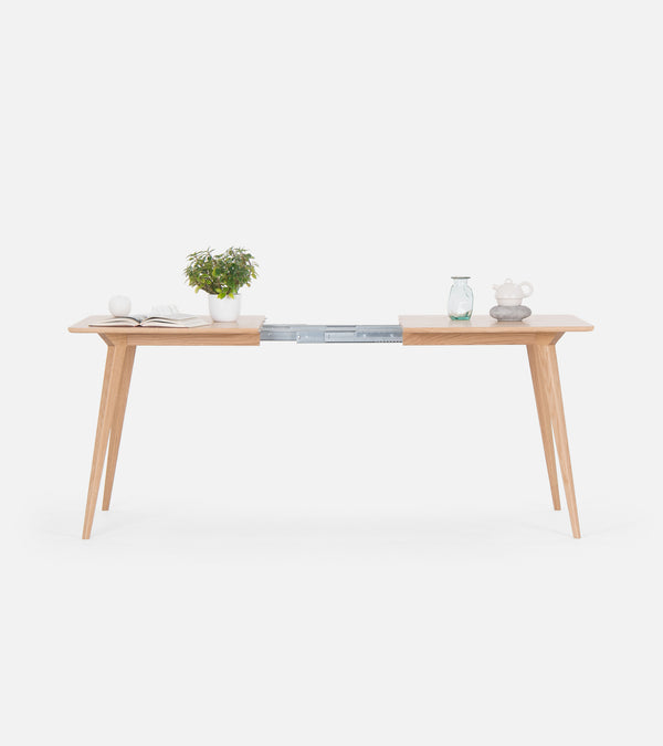 Minimalist wooden table with plants and ornaments, featuring a sliding extension in the middle.