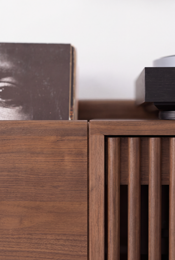 FUSE X in solid walnut, close-up of the top corner and rounded door slats beneath a record sleeve and turntable edge
