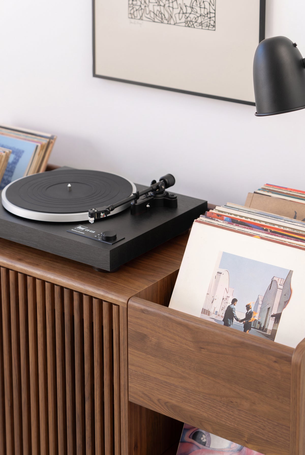 Close-up of the FUSE X in solid walnut with a turntable on top beside a niche holding records