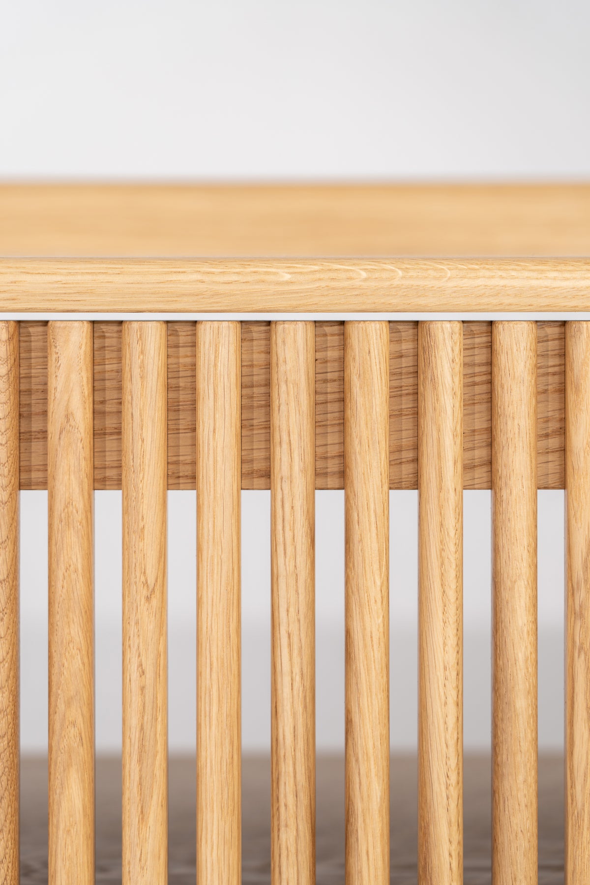 Front close-up of the FUSE XX in solid oak showing rounded vertical door slats beneath the rounded top edge