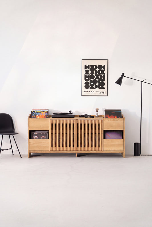Front view of the FUSE XX hi-fi unit in solid oak, both slatted doors closed beneath a turntable and records