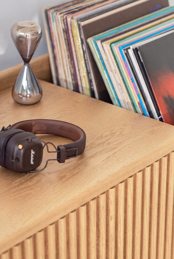 Close-up of the FUSE XX in solid oak, with headphones and an hourglass on top and records in the end niche