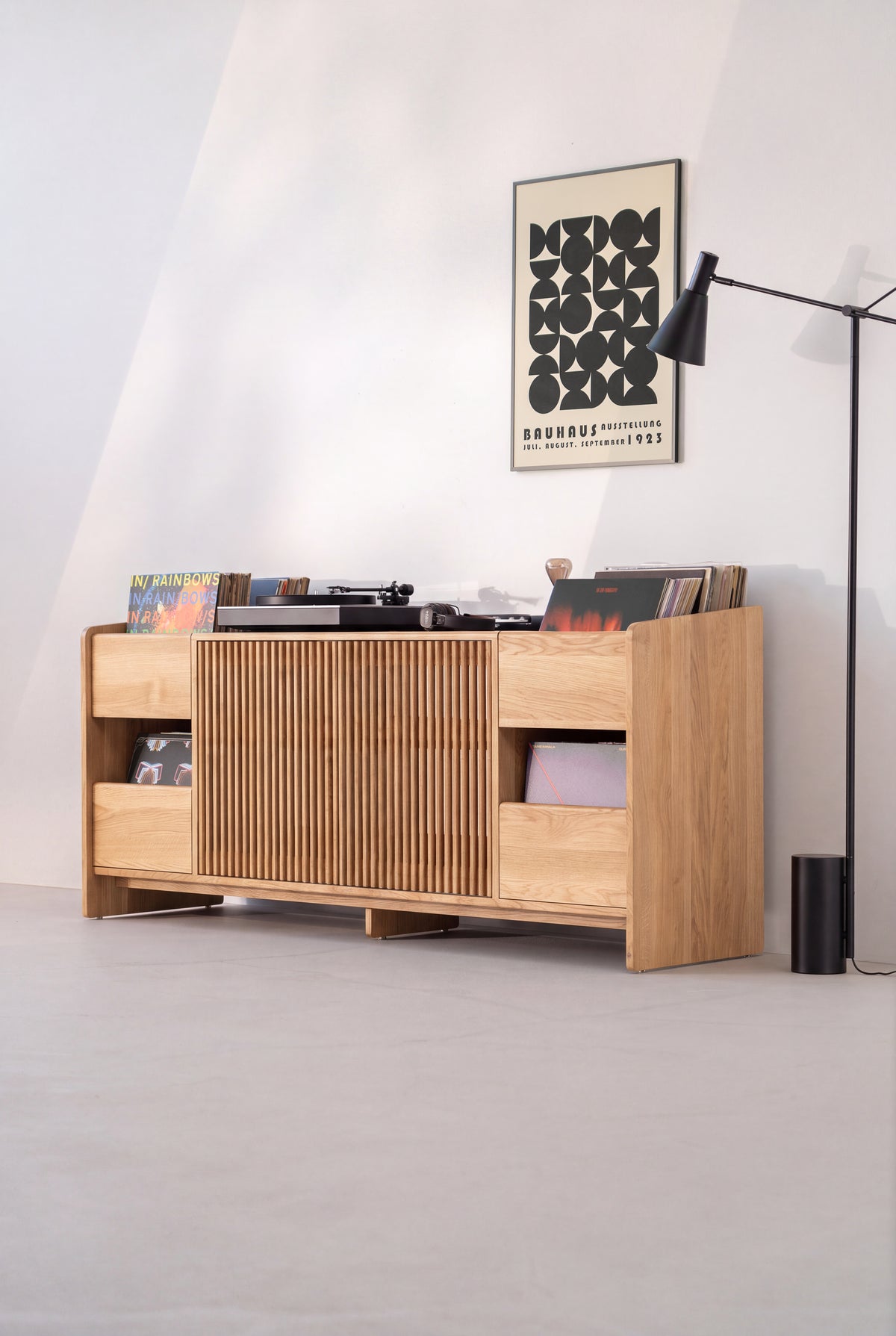 FUSE XX in solid oak at a three-quarter angle in a sunlit room, with closed doors and a turntable and records on top