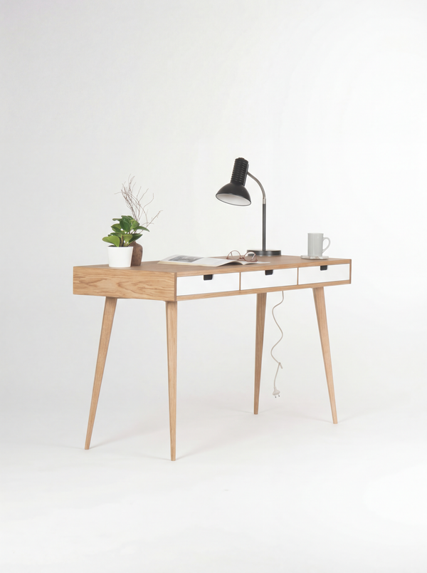 HEIM 140 desk in oak wood, angled view with white fronts, an open magazine and a lamp cable hanging behind