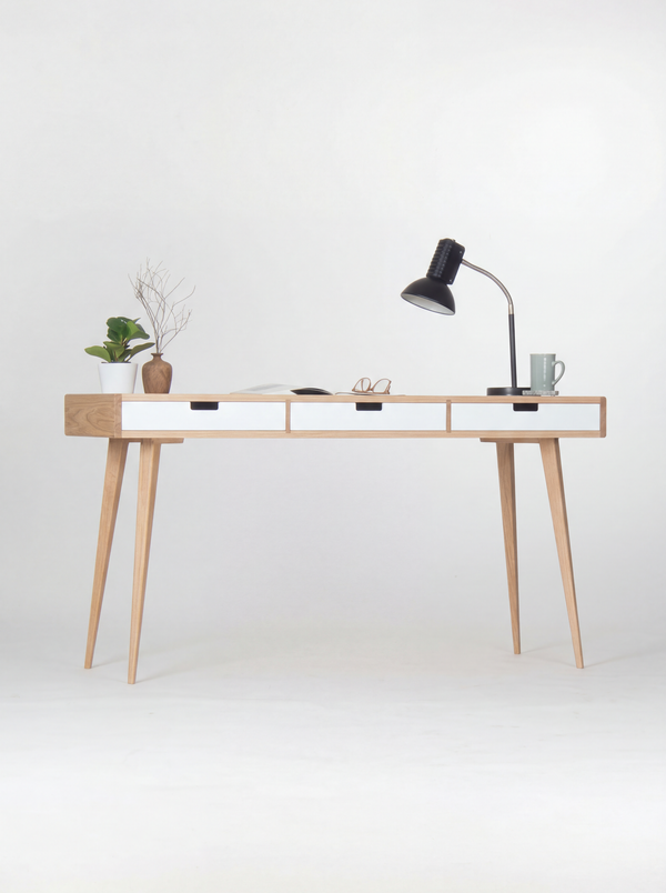 HEIM 140 desk in oak wood, full view with white drawer fronts, splayed legs, a black lamp and mug