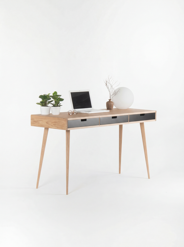 Three-quarter view of the HEIM 140 desk in oak wood, with its oak side, black drawer fronts, laptop and globe lamp