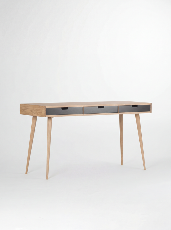 HEIM 140 desk in oak wood, shown empty at a three-quarter angle with three black drawer fronts on a white background
