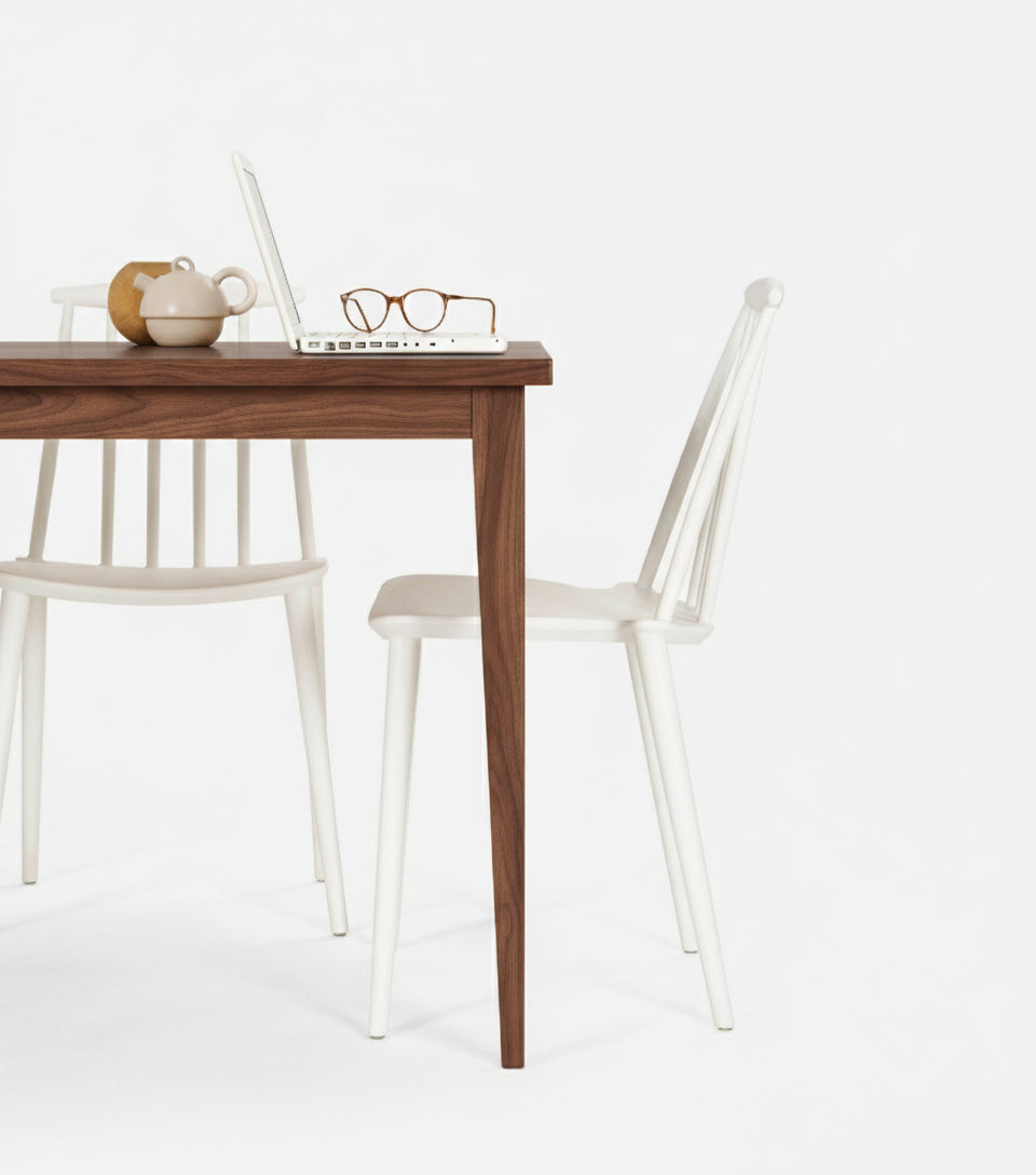  Wooden table with a laptop, glasses, and teapot; two white chairs nearby.