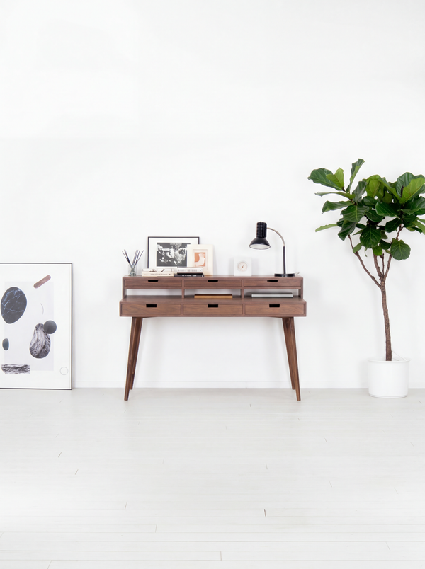 Mid-century modern console with decor, lamp, and plant in white room.