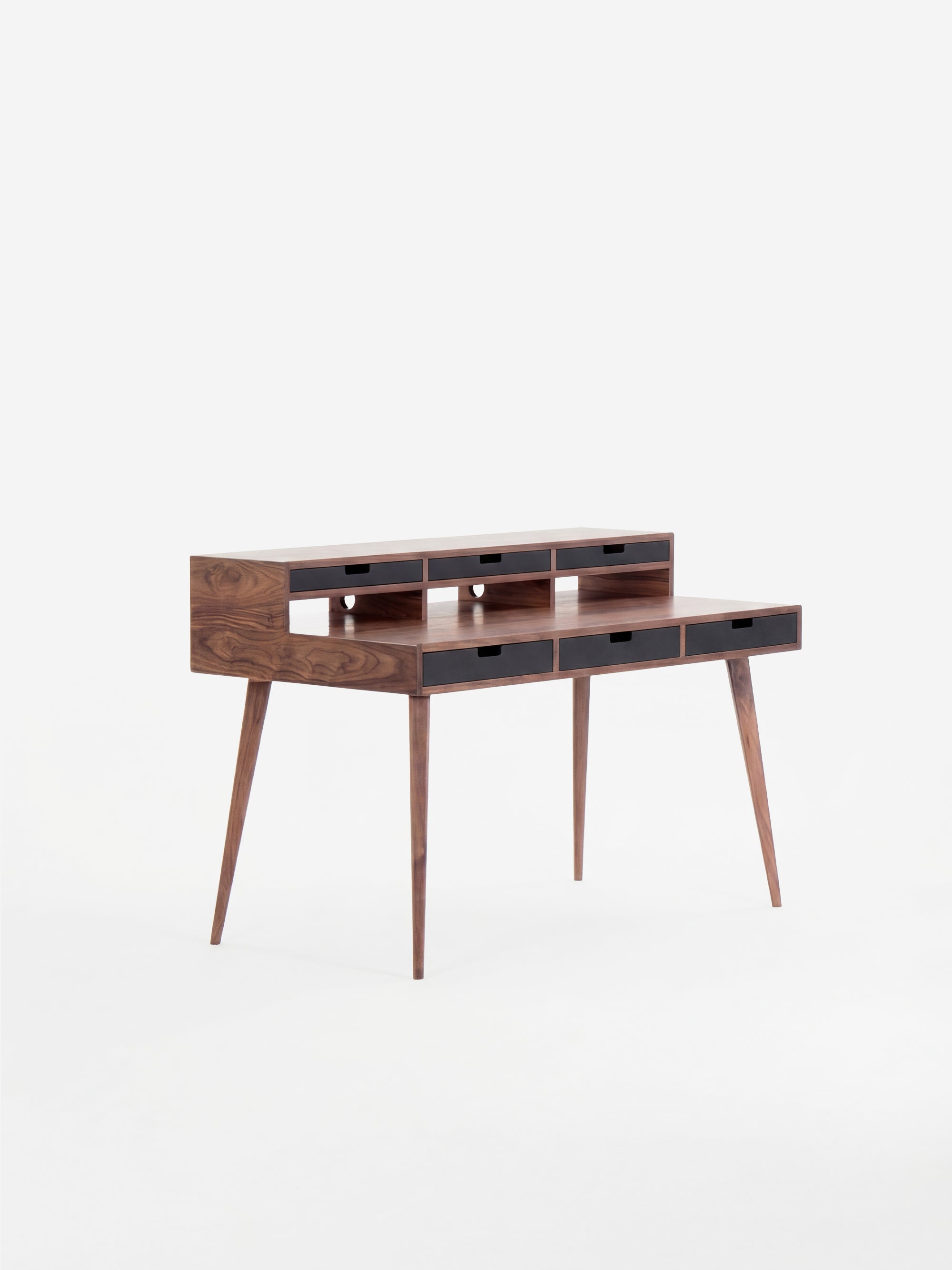 Mid-century modern wooden desk with narrow drawers and tapered legs.