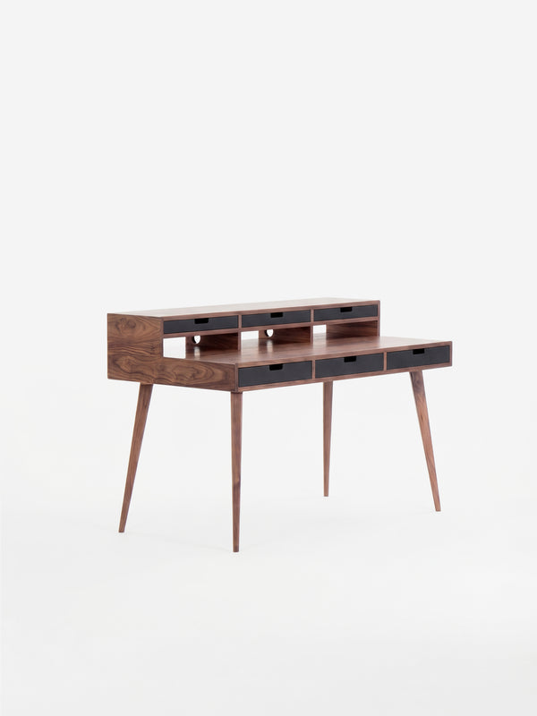 Mid-century modern wooden desk with narrow drawers and tapered legs.