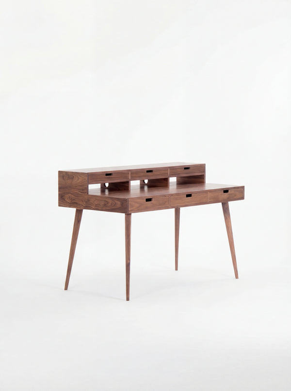 Mid-century modern wooden desk with narrow drawers and tapered legs.