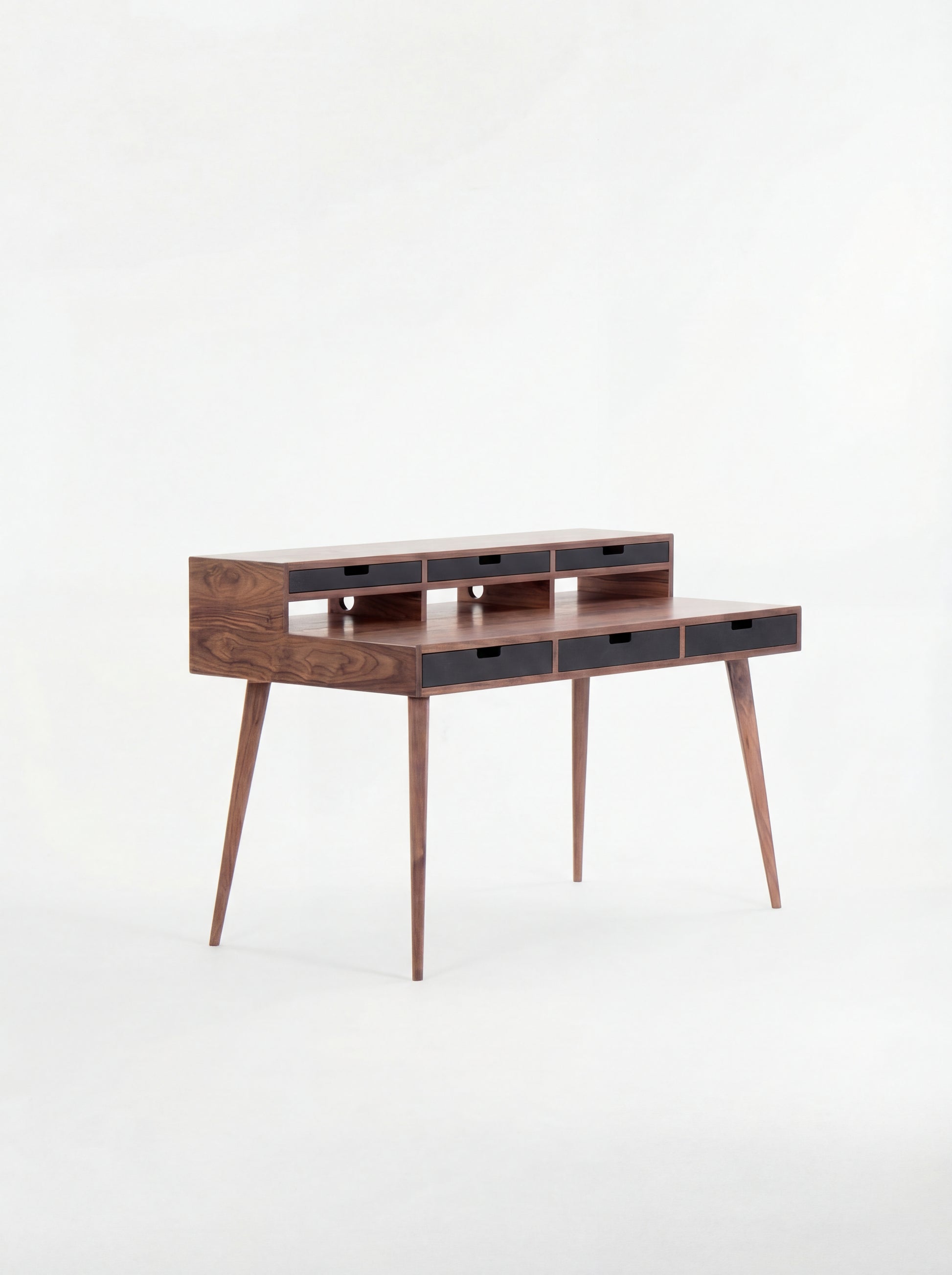 Mid-century modern wooden desk with narrow drawers and tapered legs.