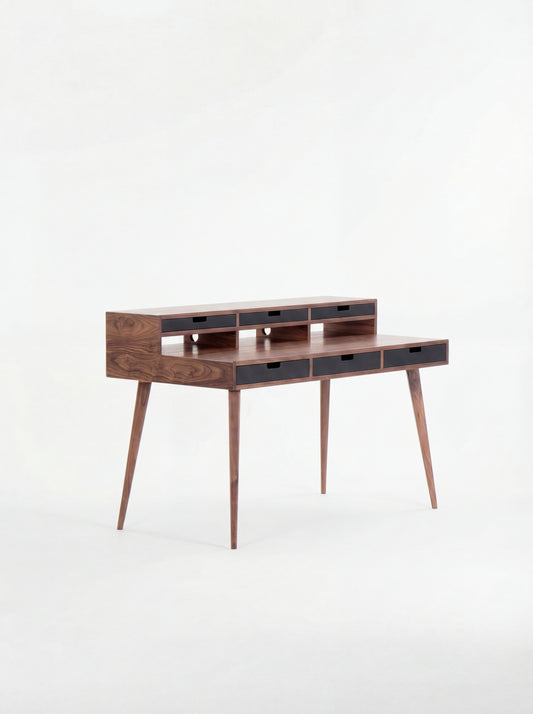 Mid-century modern wooden desk with narrow drawers and tapered legs.