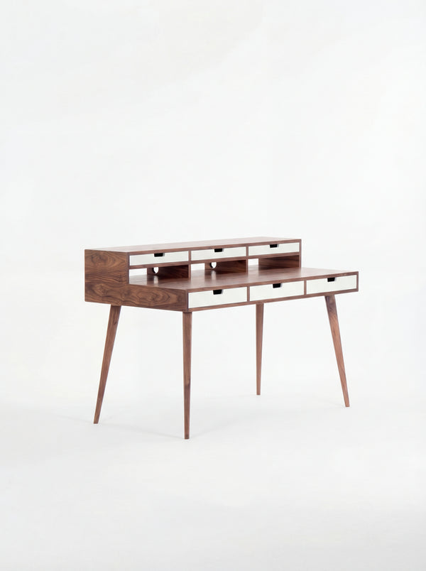 Mid-century modern wooden desk with narrow drawers and tapered legs.