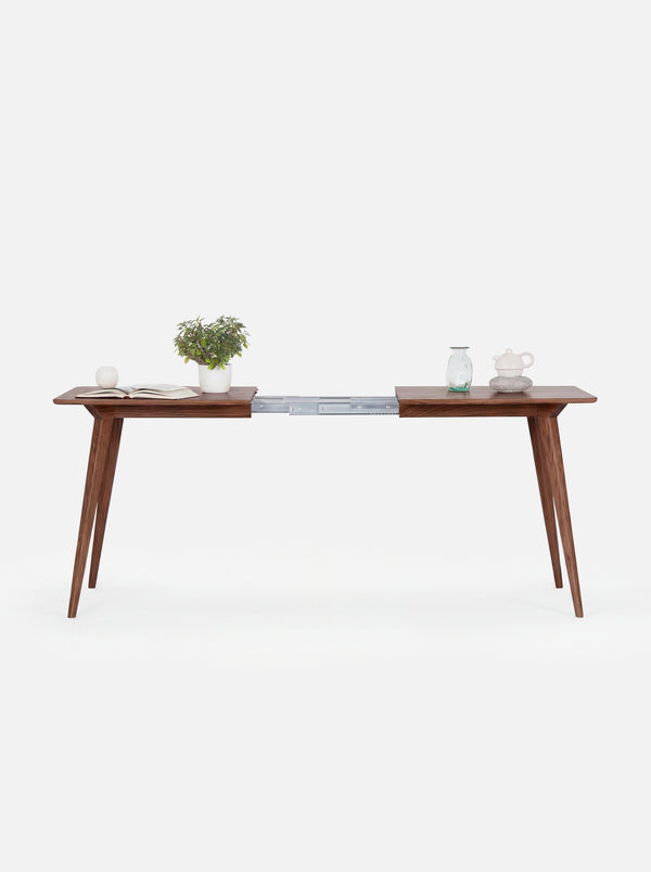 Minimalist wooden desk with tapered legs, featuring plants and ceramic items.