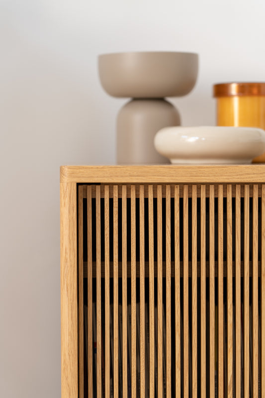 Wooden slatted cabinet with modern, neutral-toned pottery on top.