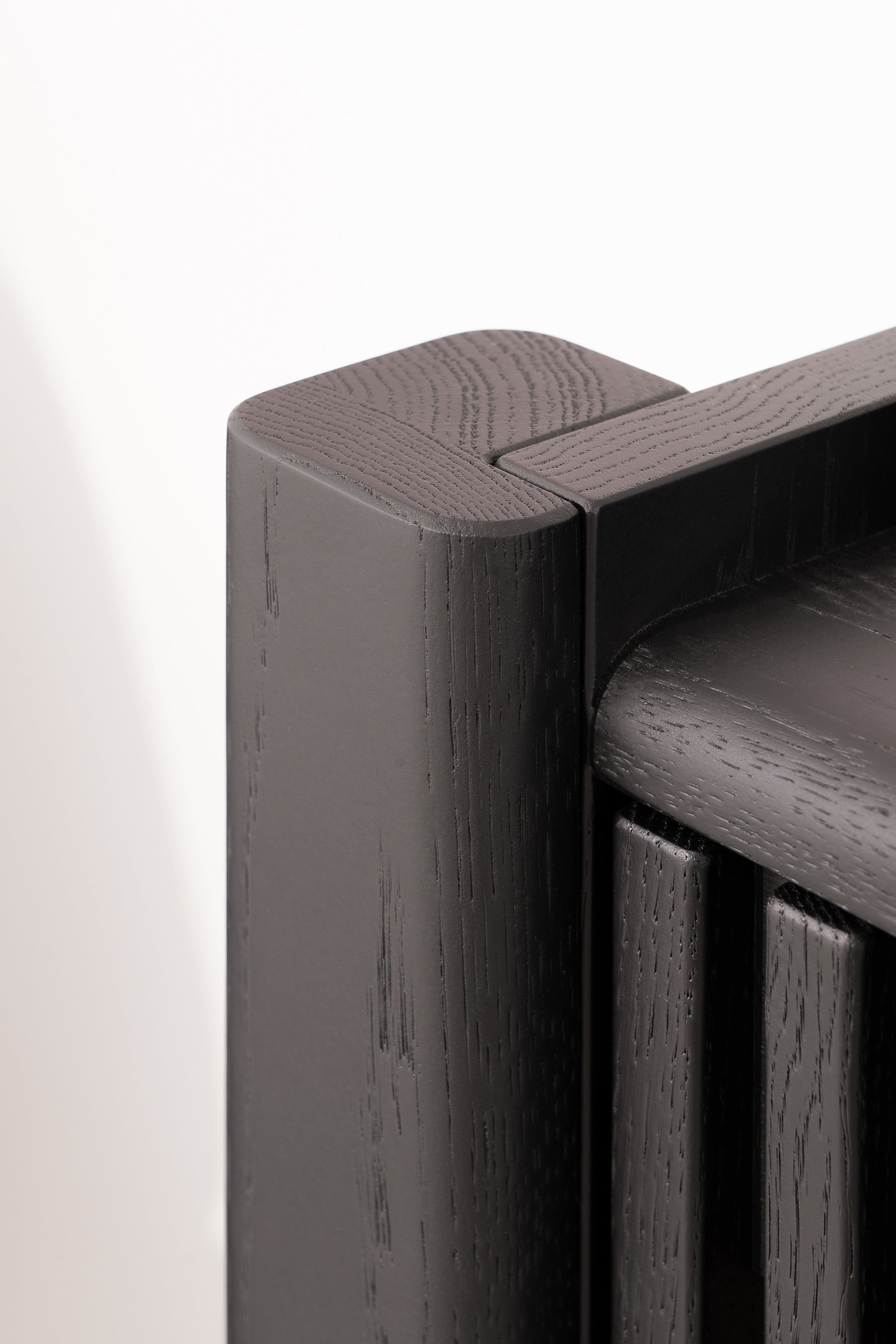 Close-up of a corner of a modern, dark wooden radiator with smooth, rounded edges.