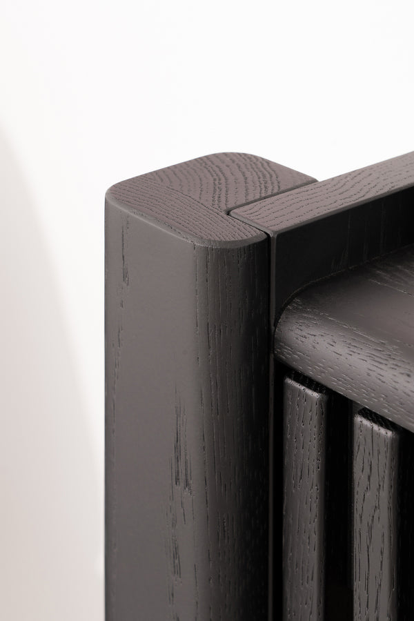 Close-up of a corner of a modern, dark wooden radiator with smooth, rounded edges.