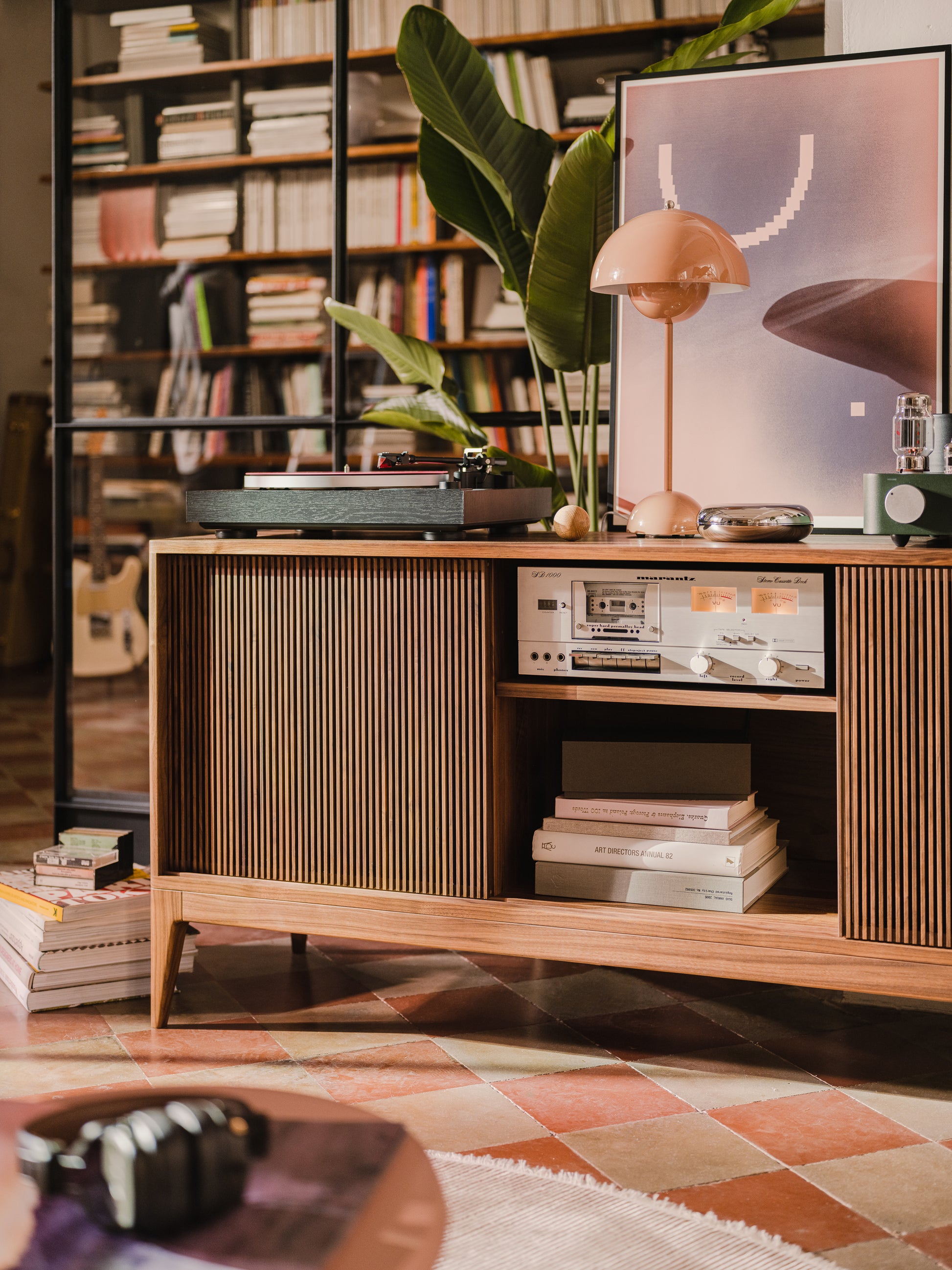 Mid-century modern interior with a wood cabinet, vinyl player, books, and a large plant.