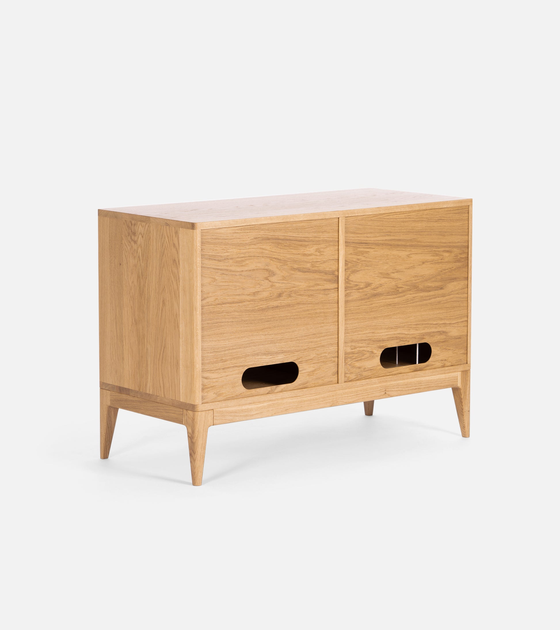 A wooden sideboard with two sliding doors, tapered legs, and cut-out handles.