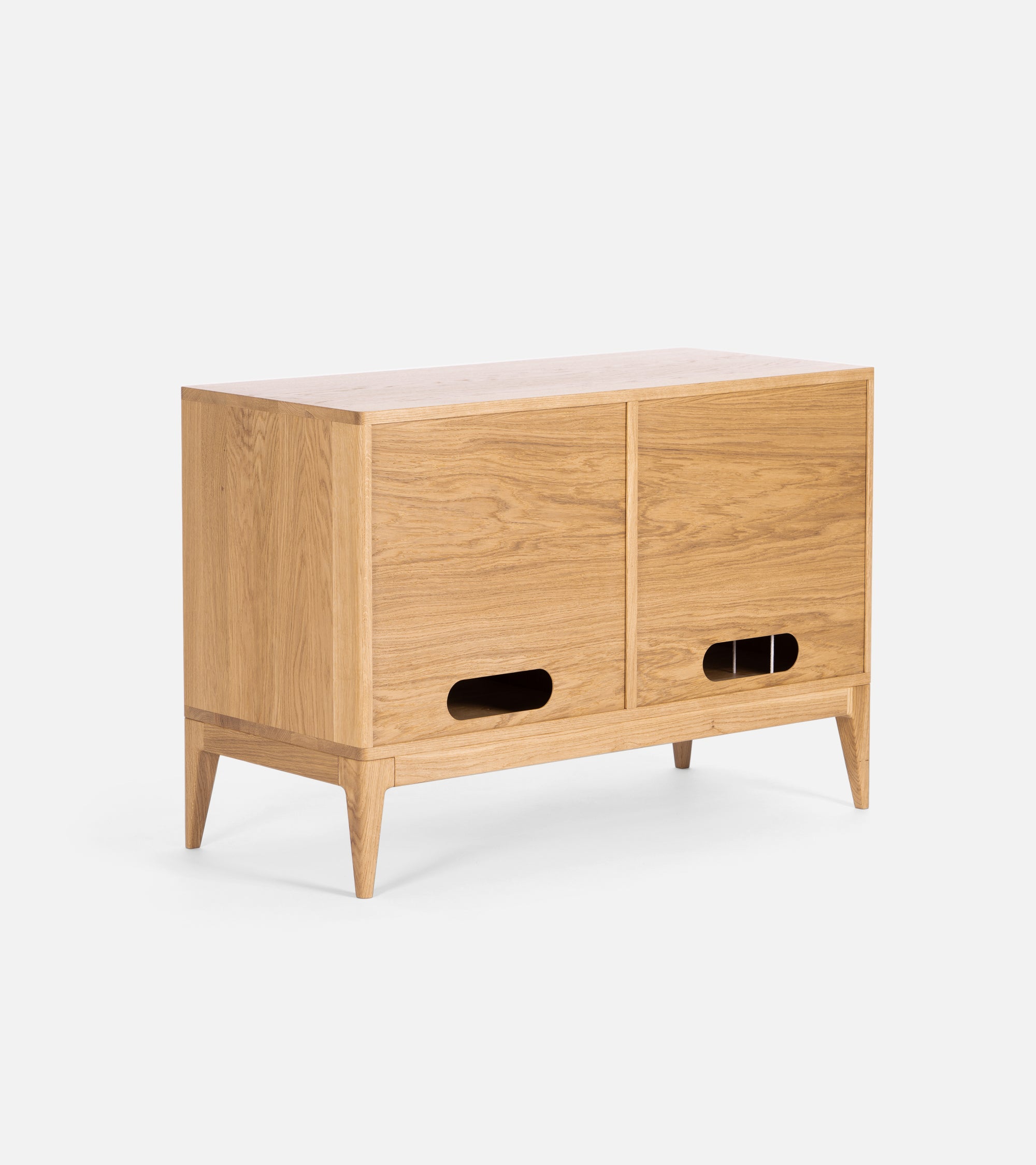A wooden sideboard with two sliding doors, tapered legs, and cut-out handles.