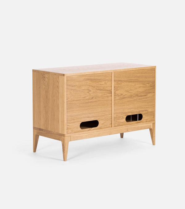 A wooden sideboard with two sliding doors, tapered legs, and cut-out handles.