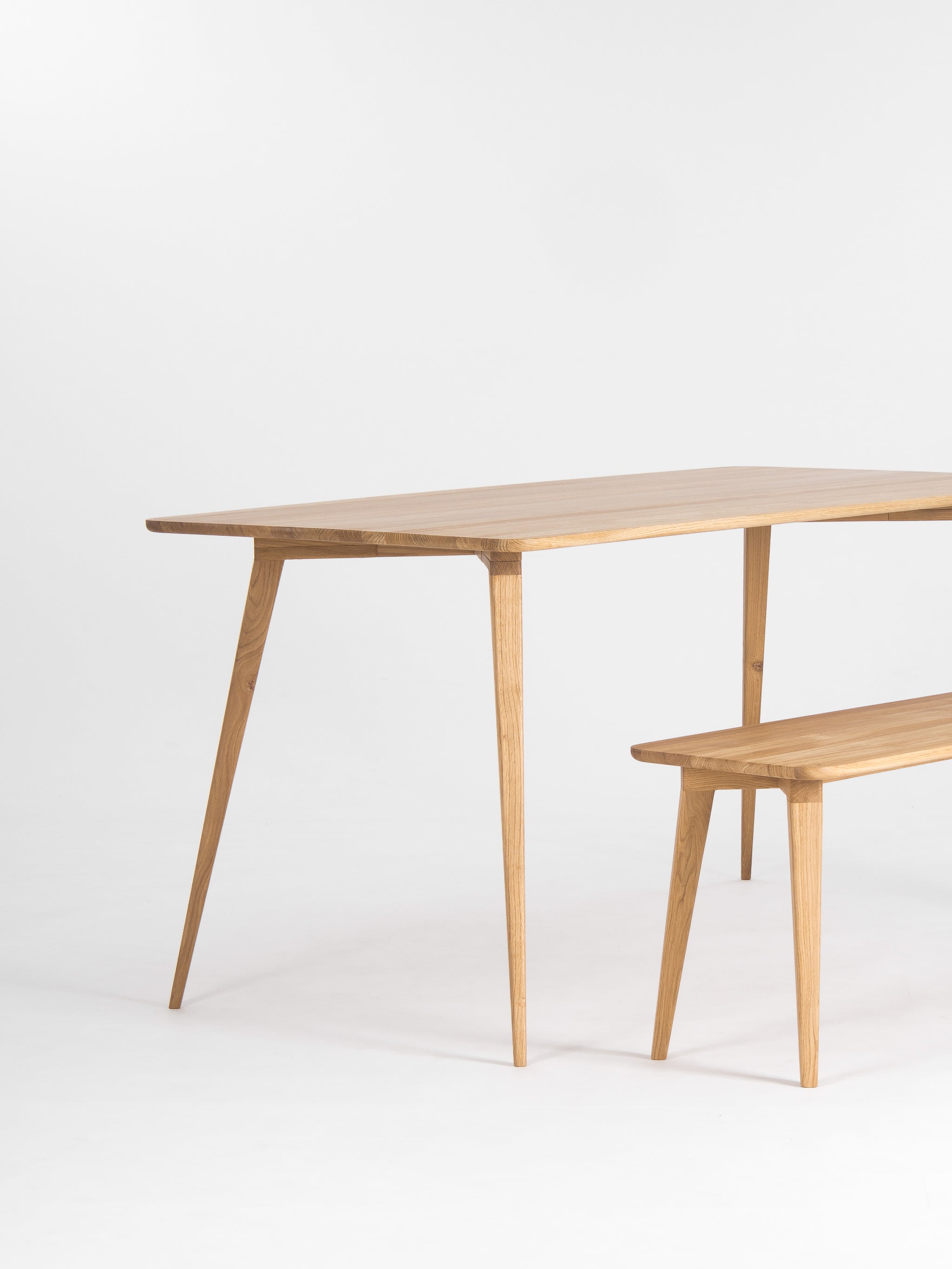 Wooden table and bench with a minimalist design on a white background.