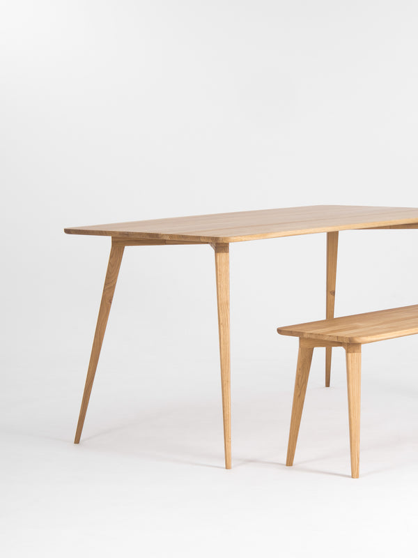 Wooden table and bench with a minimalist design on a white background.
