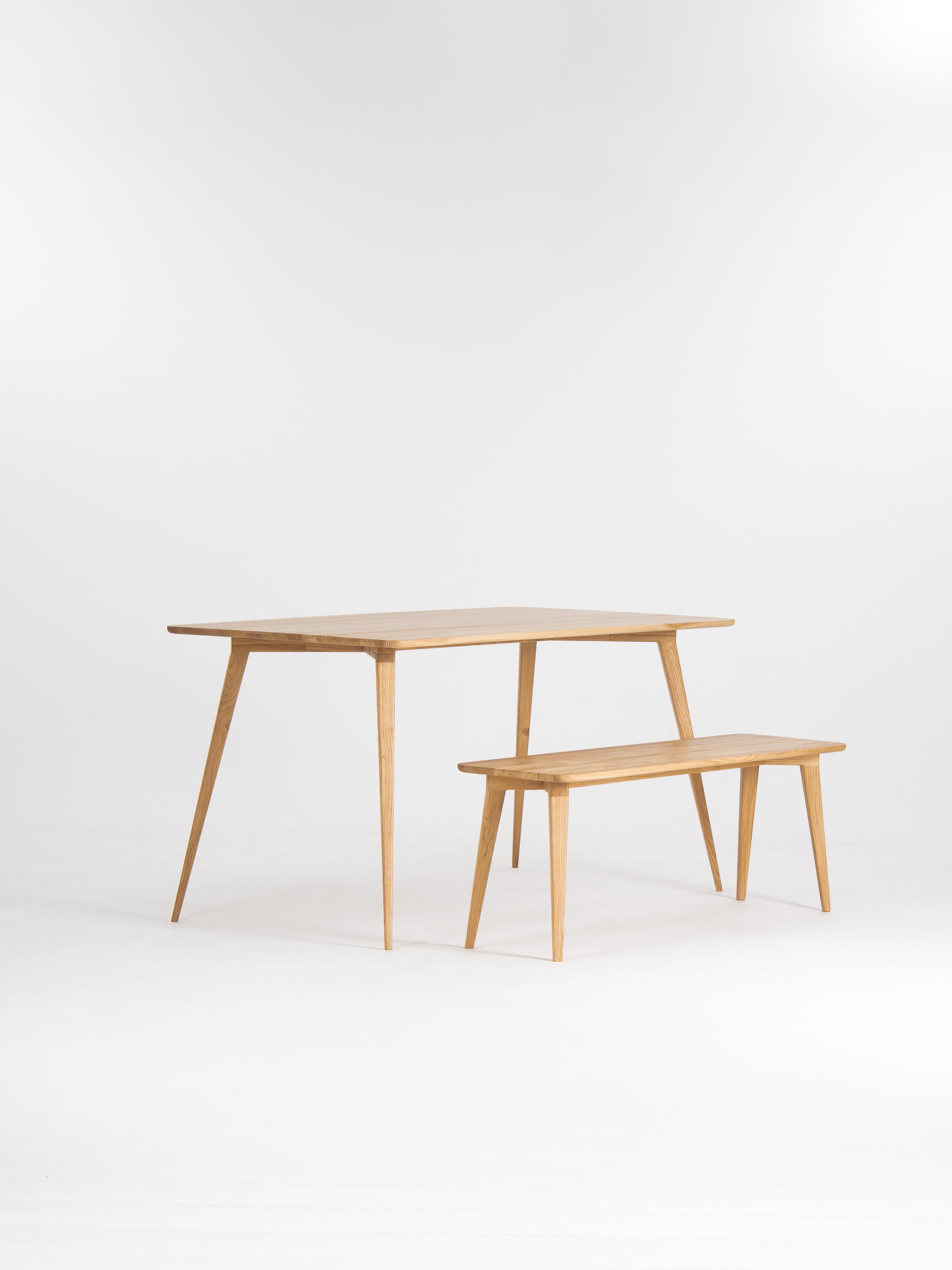 Minimalist wooden table and bench set on a white background.