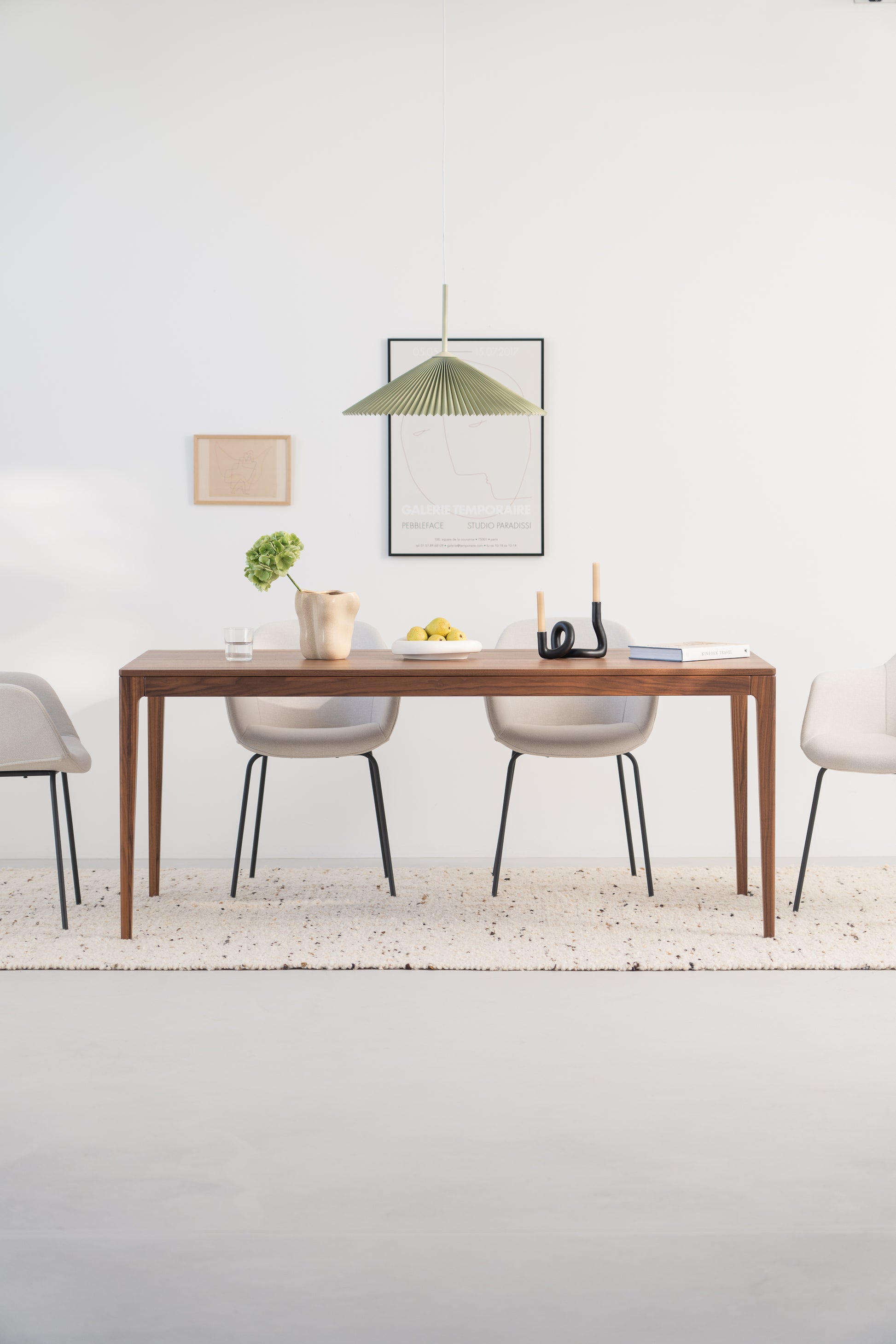 Minimalist dining room with a wooden table, modern chairs, and a green pendant lamp.