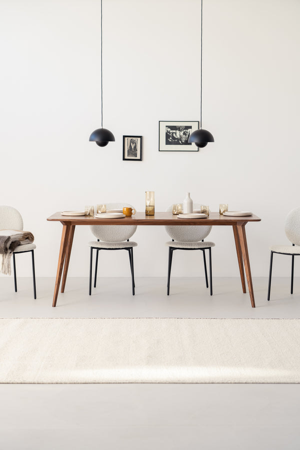 Modern dining room with a wooden table, minimal décor, four chairs, pendant lights, and framed wall art.