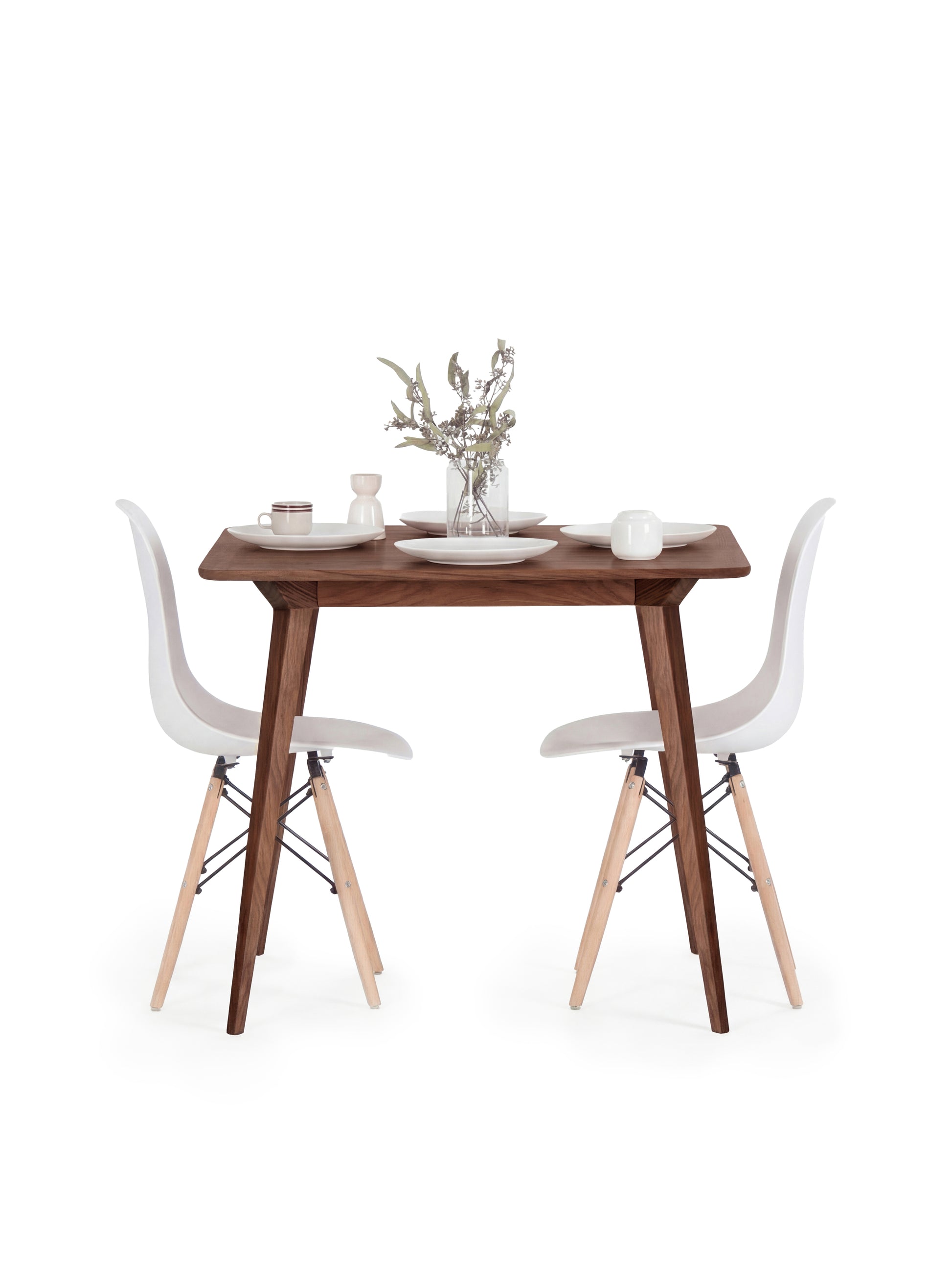 Minimalist dining setup with a wooden table, white chairs, and tableware.