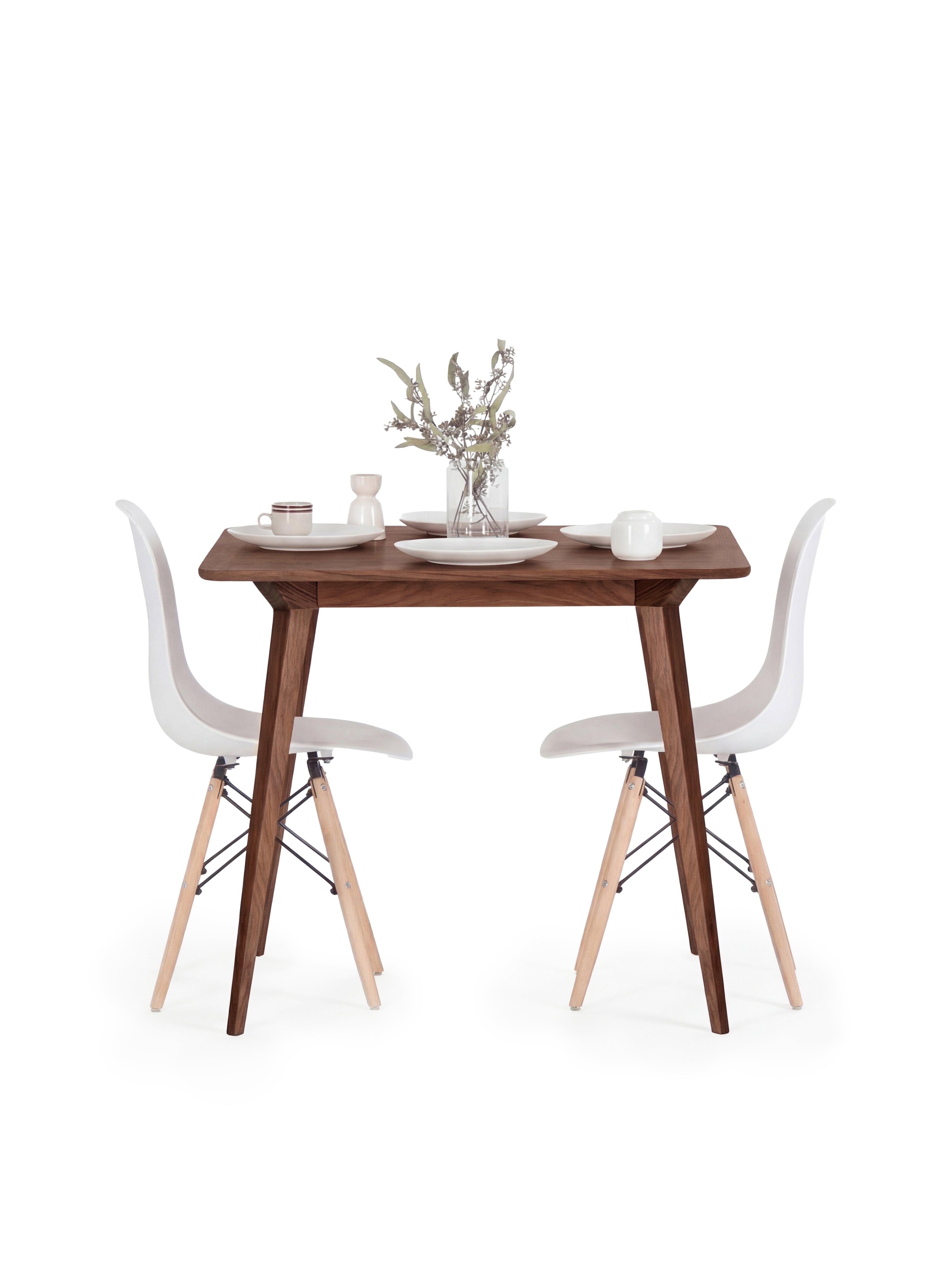 Minimalist dining setup with a wooden table, white chairs, and tableware.