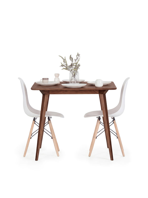 Minimalist dining setup with a wooden table, white chairs, and tableware.