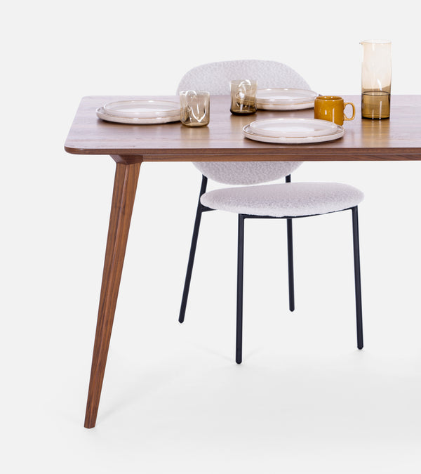 Modern dining table set with two plates, glasses, a mug, and a pitcher, paired with a white chair.