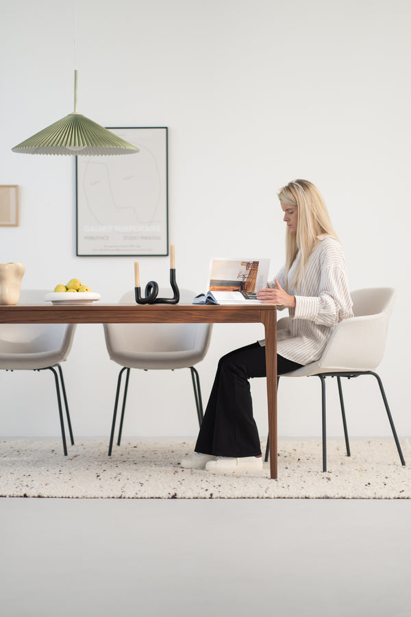 Woman reading a magazine at a modern dining table with minimalist decor.