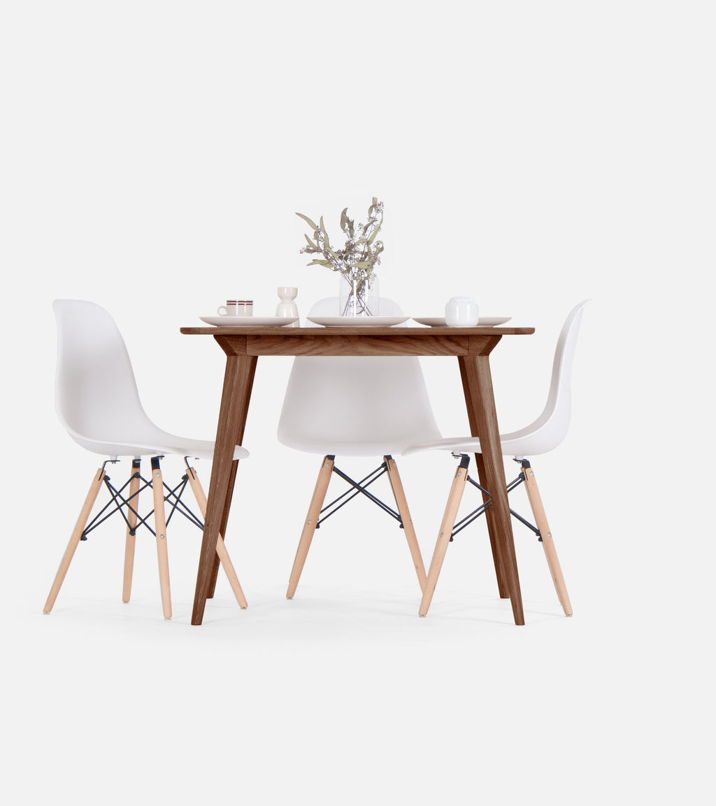  Mid-century modern table and two white chairs with minimalist table setting and vase.
