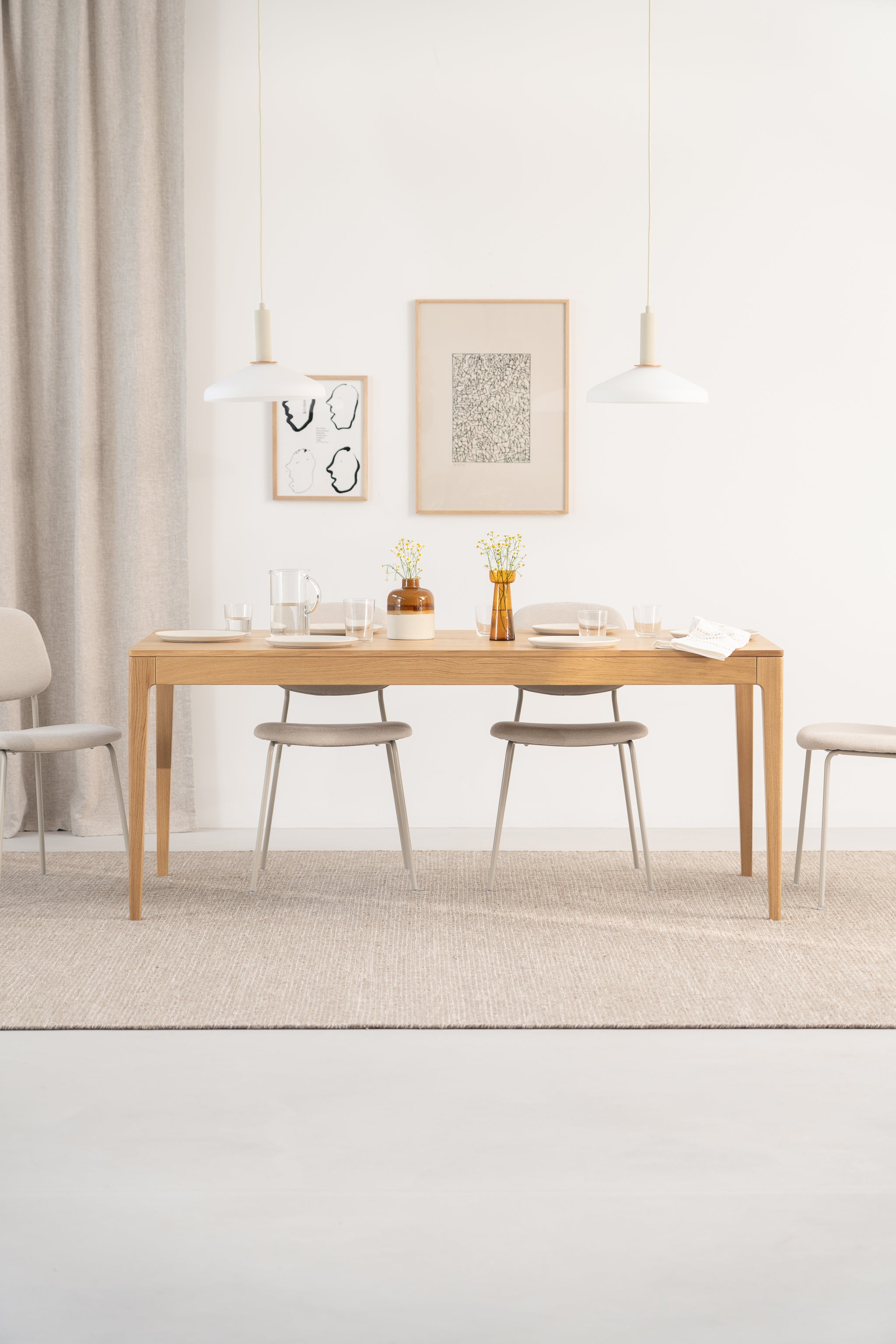 Modern dining room with wooden table, beige chairs, wall art, and pendant lights.