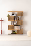 Front view of MOLL solid oak bookshelf with staggered sliding slat fronts, styled with books, records and plants