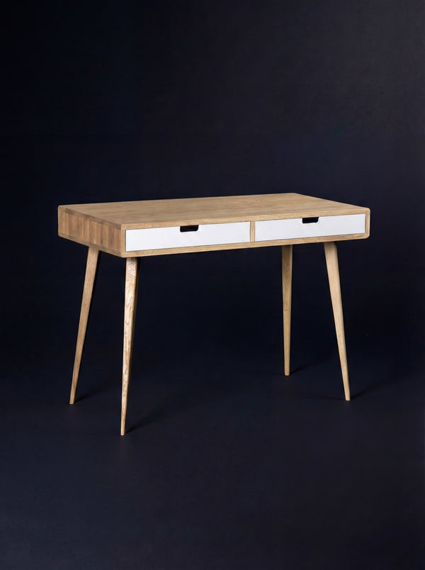 Empty HEIM 105 desk in solid oak with two white drawer fronts, seen at an angle against a dark background